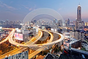 Panorama of Bangkok at dusk with skyscrapers in background and traffic trails on elevated expressways and circular interchanges photo