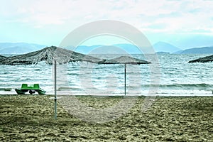 Panorama of a beach with parasol sun umbrella during a cloudy rainy afternoon on the Prespa lake on North Macedonian side.