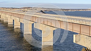 Panorama Beam bridge with deck supported by abutments or piers spanning over blue lake
