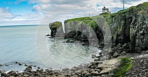 Panorama of beautiful bay near Waterford with lighthouse on the top of the cliff covered with green grass.