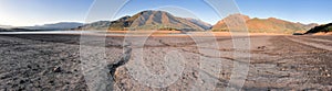Panorama beautiful landscape with setting sun: mountains, lake and cracked earth - dried-up riverbend. Copy space