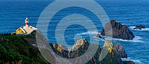 Panorama of the Cabo Ortegal lighthouse in Galicia with green cliffs and sunlight and deep blue ocean