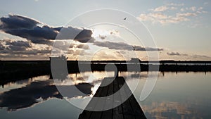 Panorama of the calm and quiet surface of the bay with a pier with sunset sun