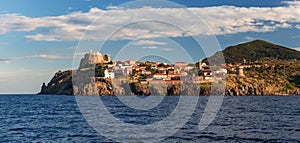 Panorama of Capraia harbour and town from the sea, rocks, yacht