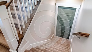 Panorama Carpeted U shaped staircase that leads down to the basement door of a home