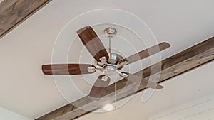 Panorama Ceiling fan with lights between decorative wood beams inside living room of home
