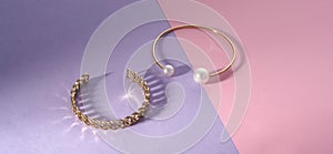 Panorama of Chain shape and golden with pearls bracelets on pink and purple paper