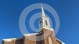 Panorama Church with classic red brick exterior wall and white steeple against blue sky