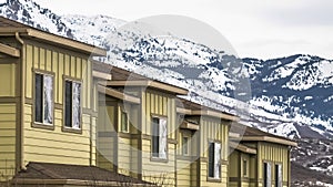 Panorama Close up of facade of townhomes with snowy mountain and cloudy sky background
