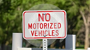 Panorama Close up view of a No Motorized Vehicle sign against a road with a white gate