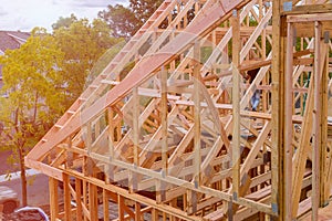 Panorama of condominium building with under construction wooden house with timber framing, truss, joist, beam close-up