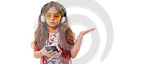 Panorama of confused girl in yellow sunglasses, with big earphones holding black smartphone isolated