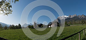 Panorama country landscape in the Swiss Alps with a farm and mountains behind