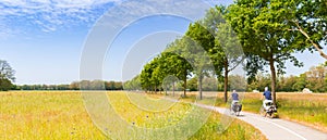 Panorama of a couple cycling in the colorful landscape near Orvelte