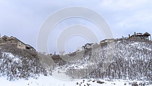 Panorama crop Homes atop gentle hill slopes with fresh snow and leafless bushes in winter