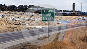 Panorama crop Passing Lane sign at the grassy side of road against snowy hill and cloudy sky