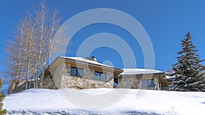 Panorama crop Stone home with snowy hip roof on a hill in Park City Utah viewed in winter