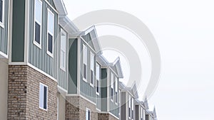 Panorama crop Upper storey of townhomes with brick wall vertical siding and snowy roofs