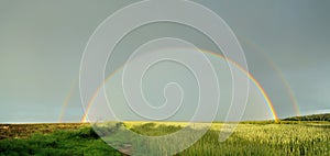 Panorama of double full rainbow over country road.