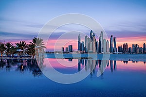 Panorama of Dubai Marina at sunset with a swimming pool in front