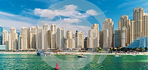 Panorama of Dubai Marina, view from sea on sandy beach and modern buildings on coastline, UAE