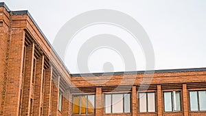 Panorama Exterior of red brick building with flat rooftop and shiny sliding windows