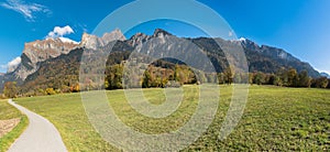 Panorama fall color mountain landscape in the Maienfeld region of Switzerland with snowy peaks and colorful trees with a meadow an