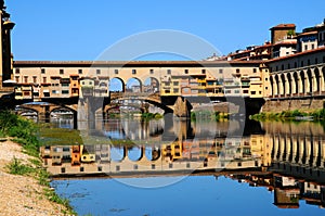 Panorama of the famous Old Bridge Ponte Vecchio and Uffizi Gallery with blue sky in Florence as seen from Arno river