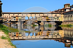 A Beautiful view of the famous Old Bridge Ponte Vecchio and Uffizi Gallery with blue sky in Florence as seen from Arno river