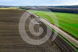 Panorama of a farmer`s field top view. The tractor makes organic fertilizers