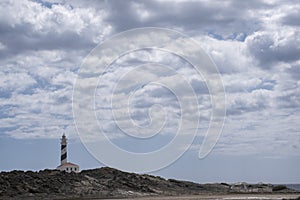 panorama of Favaritx lighthouse, with a rock formation around it on a cloudy summer day, horizontal, copy space, Menorca, Balearic