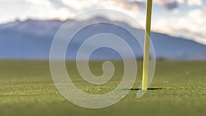 Panorama Focus on golf course yellow flagstick and hole in the middle of putting green