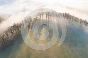 Panorama of a forest shrouded by low clouds. Rays of the sun. Autumn weather