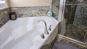 Panorama frame Built in white bathtub and shower stall inside a bathroom with marble wall