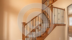 Panorama frame Carpeted stairs with wood handrail and metal railing inside an empty new home photo