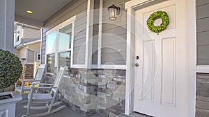 Panorama frame Facade of a home with a simple wreath hanging on the white wooden door