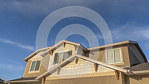 Panorama frame Home with front gable roof and dormers against vast blue sky with clouds