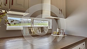 Panorama frame Laundry room interior with cabinets and window above the brown wooden countertop