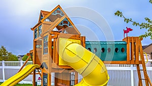 Panorama frame Playground at the backyard of a home inside a white wooden fence.