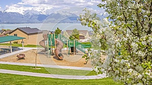 Panorama frame Playground and residential area against lake and mountain under cloudy blue sky