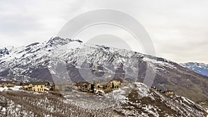 Panorama frame Snowy mountain with leafless trees multi storey homes and road viewed in winter
