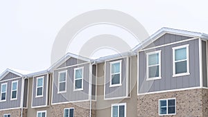 Panorama frame Upper storey of townhomes with snowy pitched roofs on a cold winter day