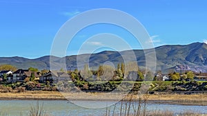 Panorama frame View of a lake with beautiful houses near the shore with brown grasses
