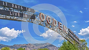 Panorama frame The welcome arch in Ogden Utah against vibrant trees and towering mountain photo