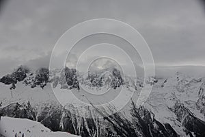 Panorama of French Alps with mountain ranges covered in snow and clouds in winter