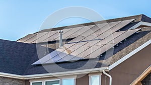Panorama Gray roof of home with solar panels and pipe vents against blue sky background