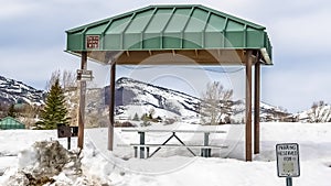 Panorama Green cabana with barbecue grill and picnic table at a snow covered park