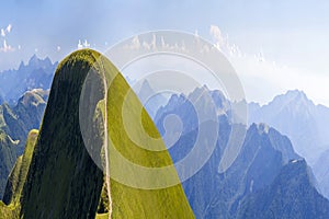 Panorama of green hills in summer mountains with gravel road for