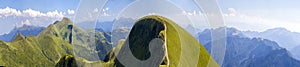 Panorama of green hills in summer mountains with gravel road for