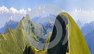 Panorama of green hills in summer mountains with gravel road for travelling by car